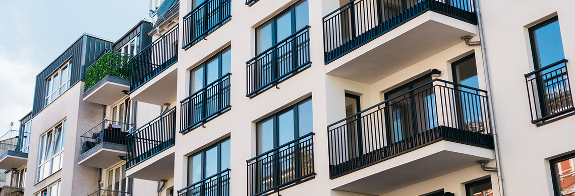 Modernes mehrstöckiges Wohngebäude mit Balkonen und großen Fenstern, heller Fassade und zeitgenössischer Architektur.
